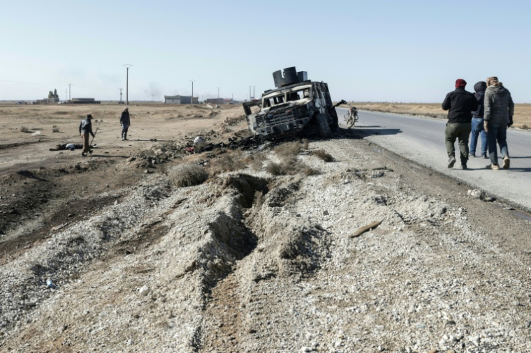 Un mort gît derrière un véhicule militaire kurde détruit au sud de la ville à majorité kurde d'Hassaké, dans le nord-est de la Syrie, le 20 janvier 2026 ( AFP / Bakr ALkasem )