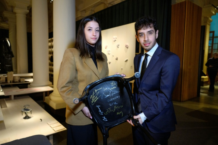 Le fils Ali Rahmani (d) et la fille Kiana Rahmani de la lauréate du prix Nobel de la paix 2023 emprisonnée, Narges Mohammadi, tiennent une chaise signée au Nobel Prize Museum, à Stockholm, le 13 décembre 2023 ( TT News Agency / Jessica Gow/TT )