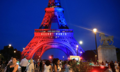 Des passants déambulent sous la Tour Eiffel, illuminée aux couleurs du Paris Saint-Germain (PSG) et sur laquelle est inscti le message "Allez Paris", avant la finale de la Ligue des champions de l'UEFA opposant le PSG à Arsenal, le 29 mai 2026 à Paris ( AFP / Ludovic MARIN )