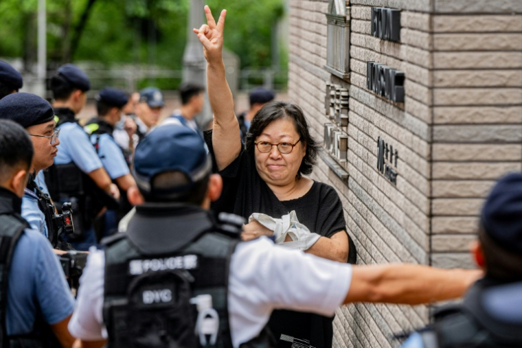 Une femme fait un signe avant d'entrer dans le tribunal pour le procès de militants prodémocratie à Hong Kong, le 21 août 2026 ( AFP / Leung Man Hei )