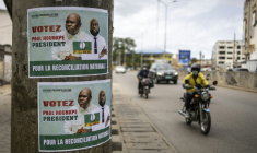 Des habitants de la capitale béninoise circulent à moto et en voiture près d'une affiche électorale, le 9 avril 2026 à Cotonou ( AFP / OLYMPIA DE MAISMONT )