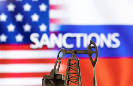 Un modèle de pompe à balancier devant le mot "Sanctions" affiché, aux couleurs des drapeaux des États-Unis et de la Russie