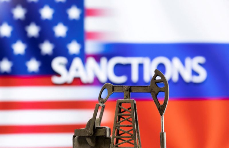 Un modèle de pompe à balancier devant le mot "Sanctions" affiché, aux couleurs des drapeaux des États-Unis et de la Russie