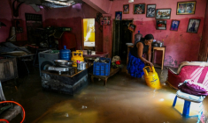 Une résidente transporte une bouteille de gaz liquéfié, dans une maison inondée, à Wellampitiya, en périphérie de Colombo, le 3 décembre 2025 ( AFP / Ishara S. KODIKARA )