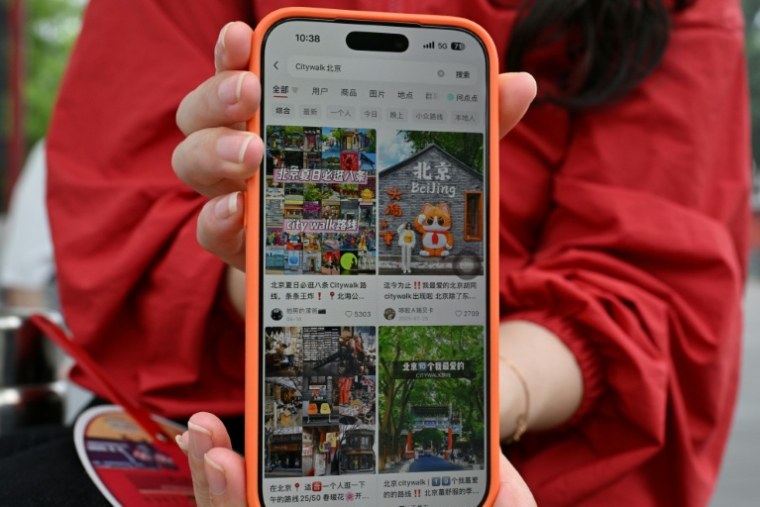 Une touriste chinoise, originaire de la province du Hunan, montre son compte Xiaohongshu sur son téléphone portable alors qu'elle visite la Cité interdite à Pékin, le 11 juillet 2026 ( AFP / ADEK BERRY )