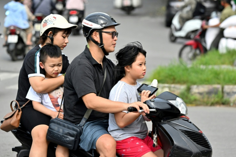 Une famille se déplace en motocyclette, le 4 juin 2025 à Hanoï ( AFP / Nhac NGUYEN )