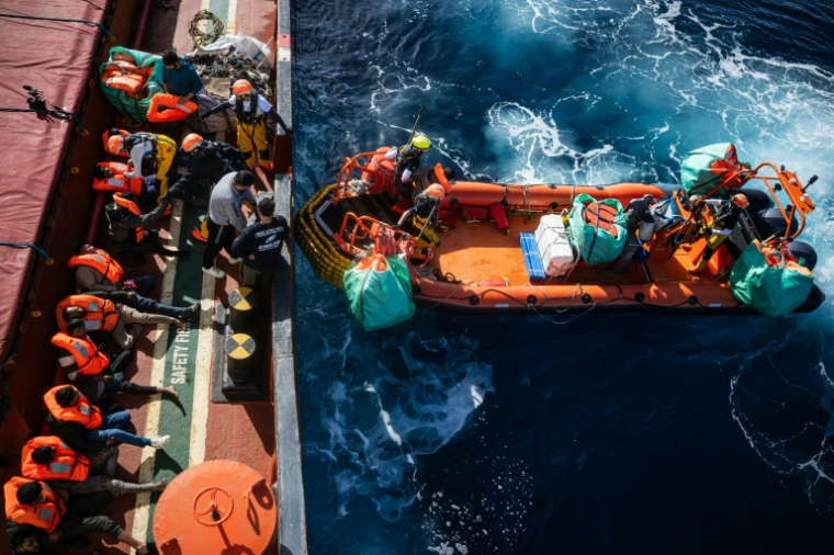 Des membres d'équipage du navire de sauvetage Ocean Viking» aident des migrants à embarquer à bord d'un semi-rigide lors de leur évacuation d'un navire marchand, dans la zone de recherche et de sauvetage située dans les eaux internationales au large des côtes libyennes, le 17 janvier 2026 ( AFP / Sameer Al-DOUMY )