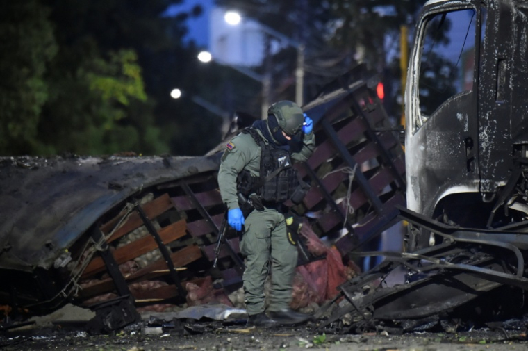 Un policier inspecte la carcasse d'un véhicule après l'explosion d'un camion bourré d'explosif près d'un commissariat de police dans la ville colombienne de Cúcuta, près de la frontière avec le Venezuela, le 1er août 2026  ( AFP / Schneyder Mendoza )
