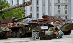 Un volontaire vend des drapeaux ukrainiens, assis sur les débris d'un missile, à Kiev, le 19 mai 2025 ( AFP / Sergei SUPINSKY )