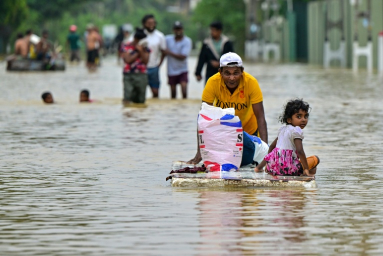 Un homme pousse une planche sur laquelle est assise une enfant dans une rue inondée après de fortes pluies à Ambatale, en périphérie de Colombo, le 29 novembre 2025 au Sri Lanka ( AFP / Ishara S. KODIKARA )