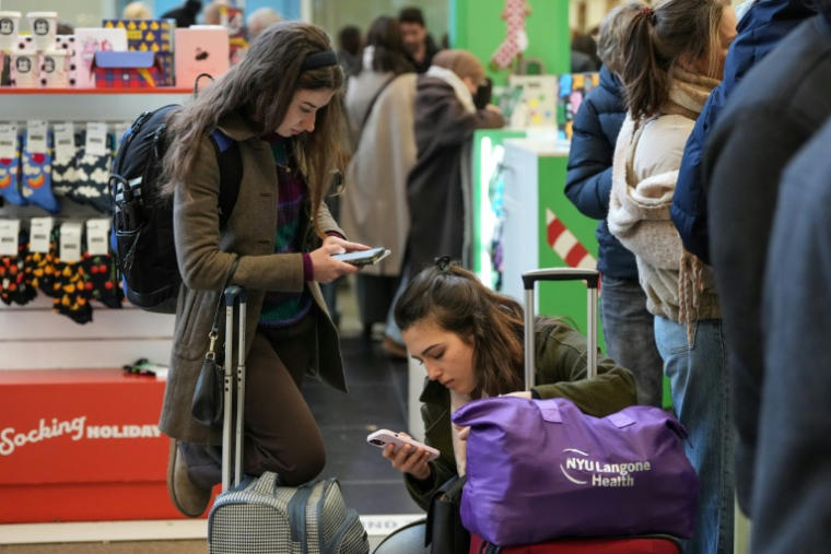 Des passagers vérifiant le "statut" de leur train sur leurs téléphones à la gare de Saint Pancras à Londres, le 30 décembre 2025, après l'annulation de plusieurs trains eurostar dûe à des problèmes techniques sous le tunnel sous la Manche ( AFP / CARLOS JASSO )