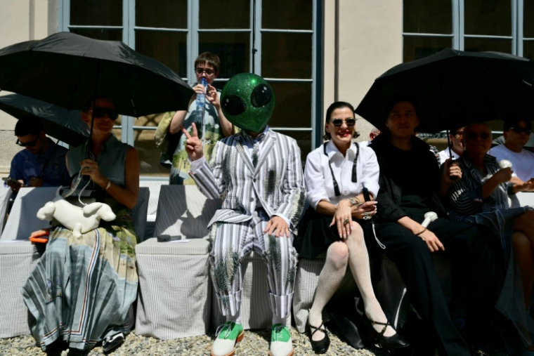 Un invité portant un masque d'extraterrestre assiste au défilé de la collection Thom Browne lors de la Fashion Week Homme Printemps/Été 2027 de Milan, à Milan, le 22 juin 2026 ( AFP / Stefano RELLANDINI )