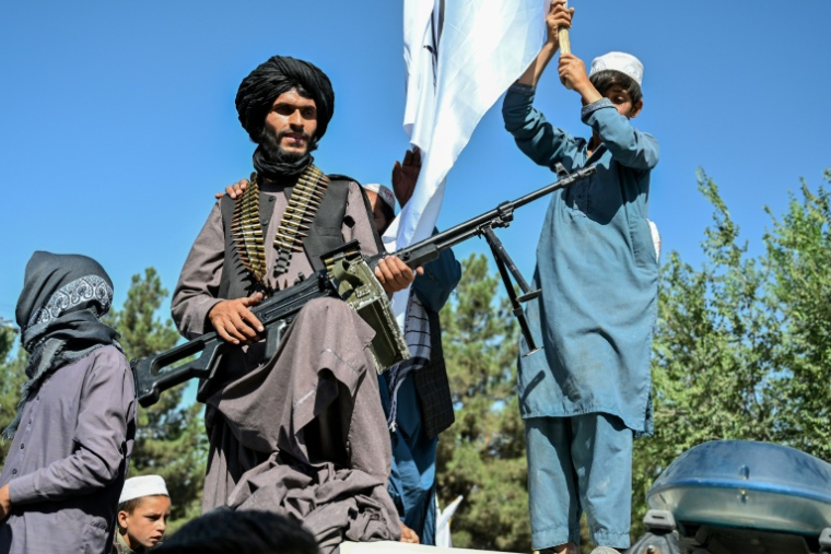 Un membre des forces de sécurité talibanes et d'autres personnes célèbrent le cinquième anniversaire de leur retour au pouvoir à Kaboul, le 15 août 2026 ( AFP / Wakil KOHSAR )