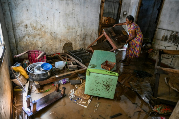 Une résidente récupère ses affaires dans une maison inondée à Wellampitiya,près de Colombo, le 3 décembre 2025 ( AFP / Ishara S. KODIKARA )