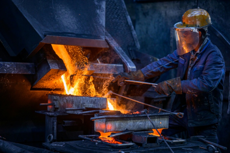 Un ouvrier verse une barre d'alliage de cuivre dans un four de fusion à l'usine de tubes MPG (Mendener Präzisionsrohr GmbH) à Menden, dans l'ouest de l'Allemagne, le 18 juin 2026 ( AFP / SASCHA SCHUERMANN )