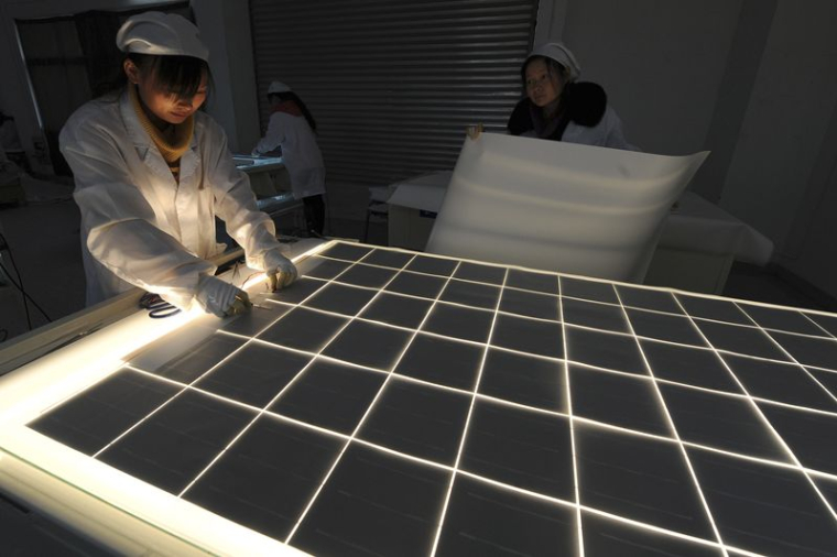 Des employés travaillent sur une ligne de production de panneaux solaires dans l'atelier d'une société solaire à Hefei