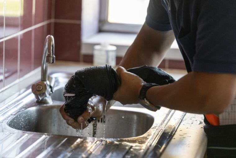 Avant utilisation, le gilet rafraîchissant doit être immergé dans l'eau fraîche et essoré, comme ici le 12 août 2025 à Châtillon, au sud de Paris ( AFP / Martin LELIEVRE )