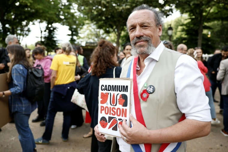 Le député de la formation "Ecologiste et Social", Benoît Biteau, pose avec une pancarte sur laquelle on peut lire "cadmium, poison" lors d'une manifestation sur l'esplanade des Invalides à Paris, le 2 juin 2026 ( AFP / SIMON WOHLFAHRT )