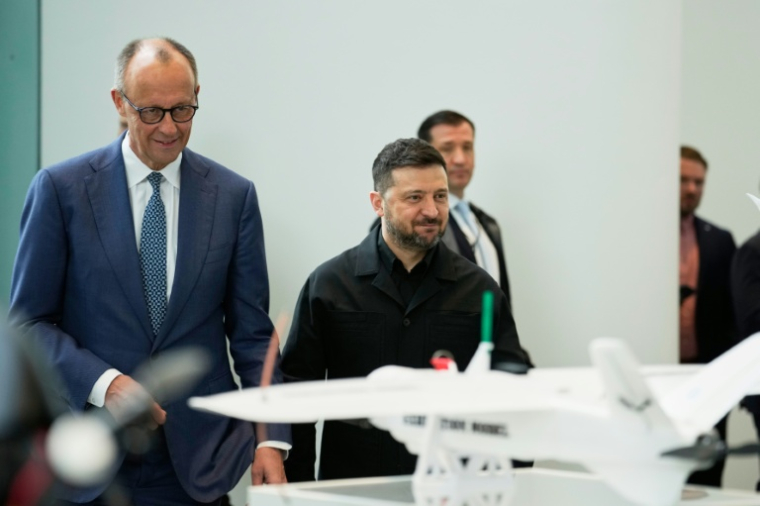 Le chancelier allemand Friedrich Merz (g) et le président ukrainien Volodymyr Zelensky (d) assistent à une présentation de drones issus de la coopération germano-ukrainienne, le 14 avril 2026 à Berlin ( POOL / Ebrahim Noroozi )