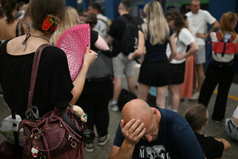 Des voyageurs attendent sur un quai de la gare centrale de Varsovie des trains retardés par la vague de chaleur, le 28 juin 2026 en Pologne ( AFP / Sergei GAPON )