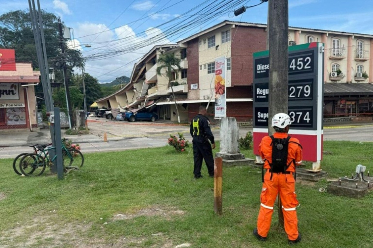 Un policier panaméen et un secouriste montent la garde à côté d'un immeuble effondré après un séisme, à Penonomé, au Panama, le 9 octobre 2026 ( AFP / Daniel DE CARTERET )