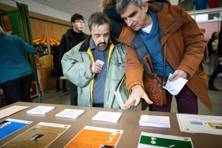 Un éducateur explique les règles pour voter lors d'un faux scrutin organisé pour des personnes en situation de handicap intellectuel, le 17 février 2026 à  Saint-Dié-des-Vosges ( AFP / SEBASTIEN BOZON )