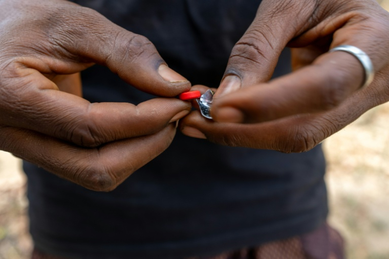 Un toxicomane tient un comprimé rouge à base de tapentadol à Abuja, le 24 février 2026 au Nigeria ( AFP / Light Oriye Tamunotonye )