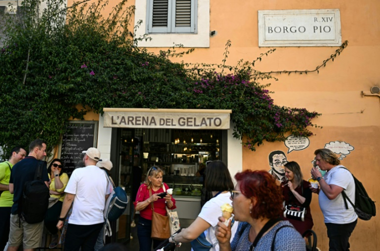Des clients mangent des glaces devant "l'Arena del gelato", via Borgo Pio, le 29 avril 2025 à Rome ( AFP / Gabriel BOUYS )