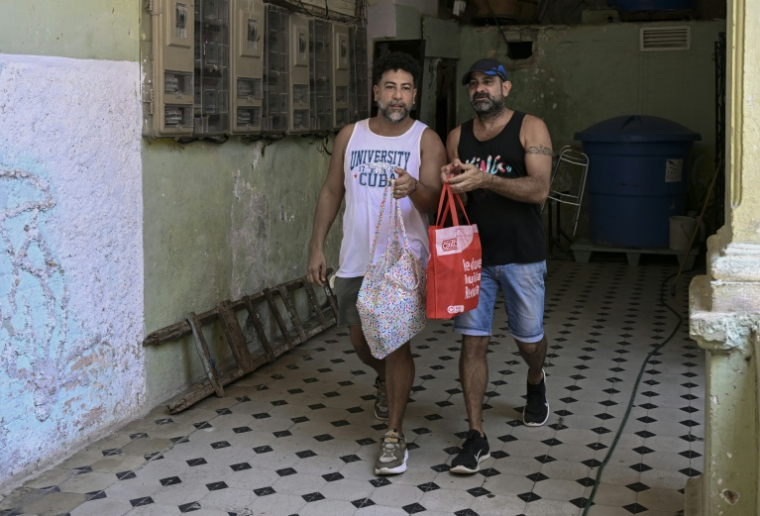 Leandro Wanton (à gauche) et Roberto Ronda, qui ont lancé un petit commerce de repas, vont livrer à pied une commande, le 31 juillet 2026 à La Havane ( AFP / YAMIL LAGE )