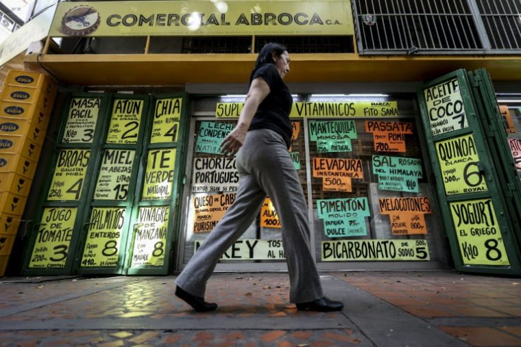 Une habitante passe devant des panneaux affichant des prix en dollars américains à Caracas, au Venezuela, le 2 juin 2025 ( AFP / Pedro MATTEY )