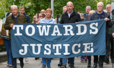 Des proches des victimes du "Bloody Sunday" brandissent une banderole sur laquelle est écrit "Towards Justice" (En faveur de la justice) alors qu'ils se rendent à pied au tribunal de Belfast, en Irlande du Nord, le 16 octobre 2025 ( AFP / Paul Faith )