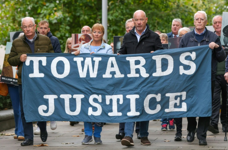 Des proches des victimes du "Bloody Sunday" brandissent une banderole sur laquelle est écrit "Towards Justice" (En faveur de la justice) alors qu'ils se rendent à pied au tribunal de Belfast, en Irlande du Nord, le 16 octobre 2025 ( AFP / Paul Faith )