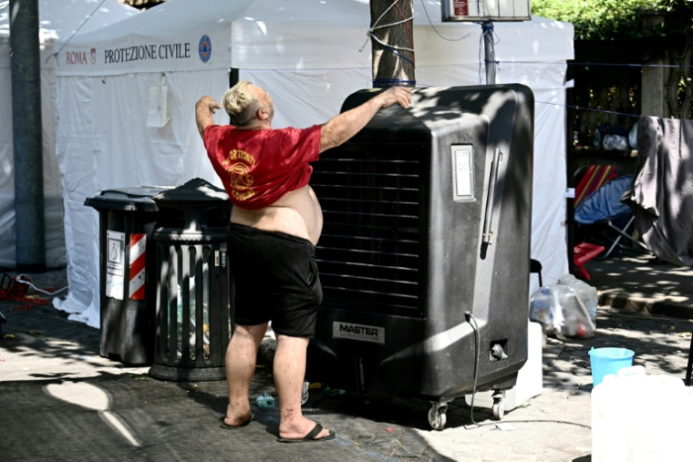 Marco Perilli, un ancien résident d'un centre social à Rome vidé récemment de ses occupants, se rafraîchit devant un ventilateur, le 11 août 2026 à Rome ( AFP / Filippo MONTEFORTE )
