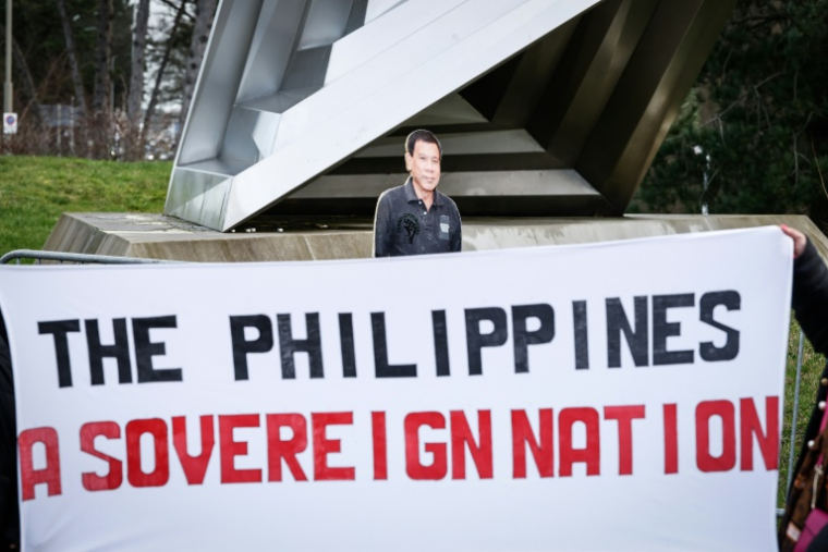 Une silhouette en carton de l'ancien président philippin Rodrigo Duterte et une banderole "Les Philippines, une nation souveraine" lors d'une manifestation de soutien devant la Cour pénale internationale (CPI) à La Haye, le 23 février 2026 ( AFP / Simon Wohlfahrt )