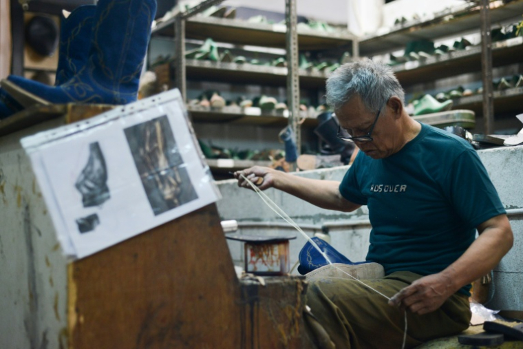 Un ouvrier fabrique une botte qui doit être livrée au marché américain dans l'atelier Tegep Boots, à Bandung (ouest de Java), le 15 juillet 2025 ( AFP / Timur MATAHARI )