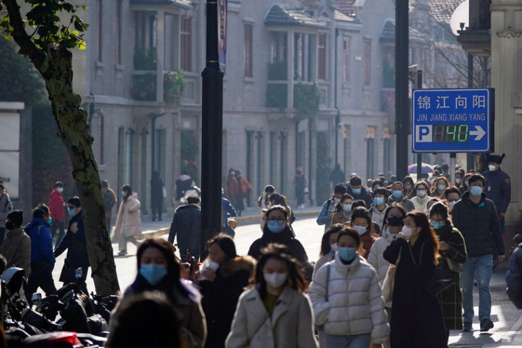 Des personnes portant des masques de protection marchent dans une rue à Shanghai, en Chine