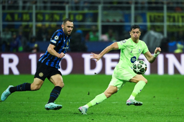 Le défenseur de l'Inter Milan Stefan de Vrij et l'attaquant barcelonais Robert Lewandowski (d) à la lutte lors de la demi-finale retour de Ligue des champions, le 6 mai 2025 à Milan ( AFP / PIERO CRUCIATTI )