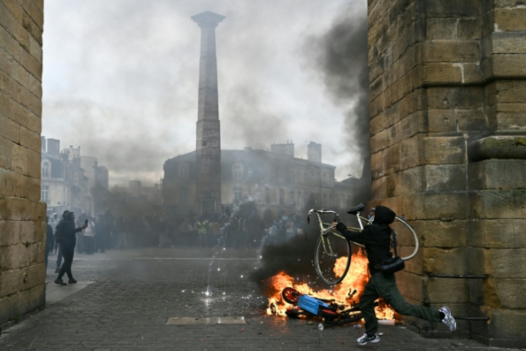 Un manifestant soulève un vélo à côté d’un feu lors d’une manifestation contre la vie chère, place de la Victoire à Bordeaux, en Gironde ( AFP / Christophe ARCHAMBAULT )
