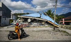 Une moto s'arrête le 16 août près d'un bâtiment effondré à la suite d'un séisme de magnitude 7,7 qui a secoué samedi l'île de Florès, en Indonésie ( AFP / JUNI KRISWANTO )