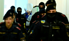 Deux accusés, escortés par des policiers, cachent leurs visages à leur arrivée à la salle d'audience du tribunal de Wiener Neustadt, en Autriche, le 28 avril 2026, pour un projet d'attentat lors d'un concert de Taylor Swift à Vienne ( APA / ROLAND SCHLAGER )