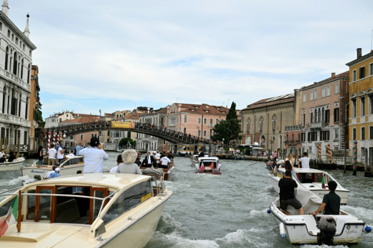 Le bateau "Moa" (c), transportant Jeff Bezos, est escorté sur le Grand Canal le jour de son mariage avec Lauren Sanchez, le 27 juin 2025 à Venise ( AFP / Stefano Rellandini )