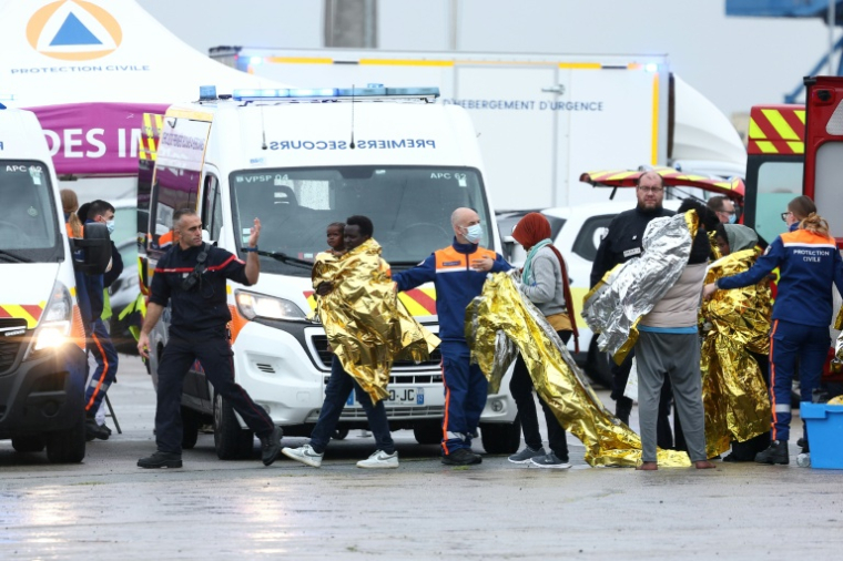 Des rescapés du naufrage d'un taxi-boat tentant de traverser la Manche en couverture de survie sont pris en charge par les secours dans le port de Calais, dans le Pas-de-Calais, le 28 septembre 2026 ( AFP / Sameer AL-DOUMY )