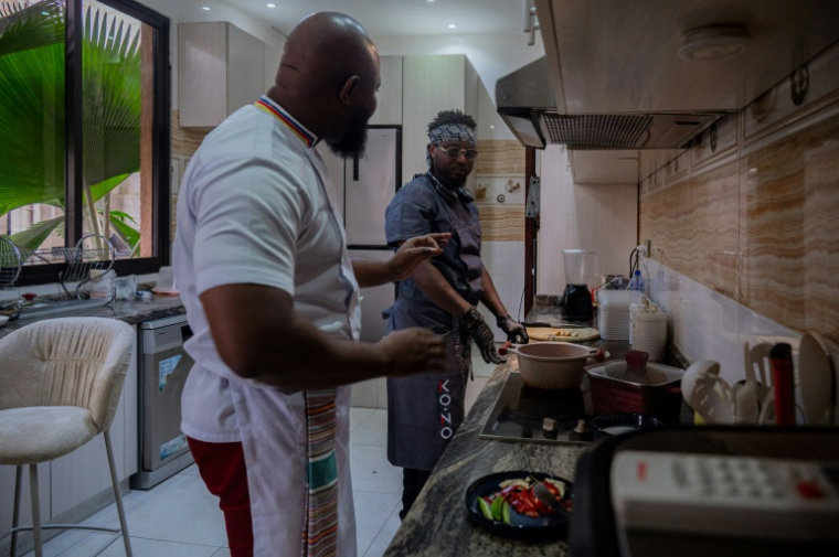 Le chef congolais Archi Dimosi parle avec son sous-chef lors de la préparation d'un plat dans sa cuisine, le 17 mai 2026 à Kinshasa, en RDC ( AFP / Hardy BOPE )