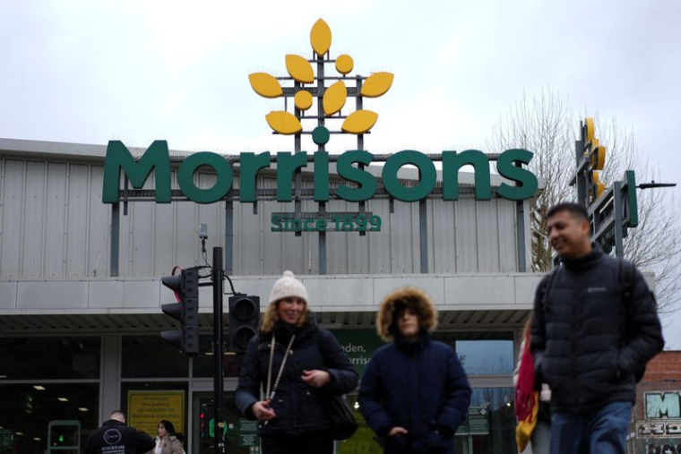 Des personnes passent devant l'entrée d'un magasin Morrisons à Londres