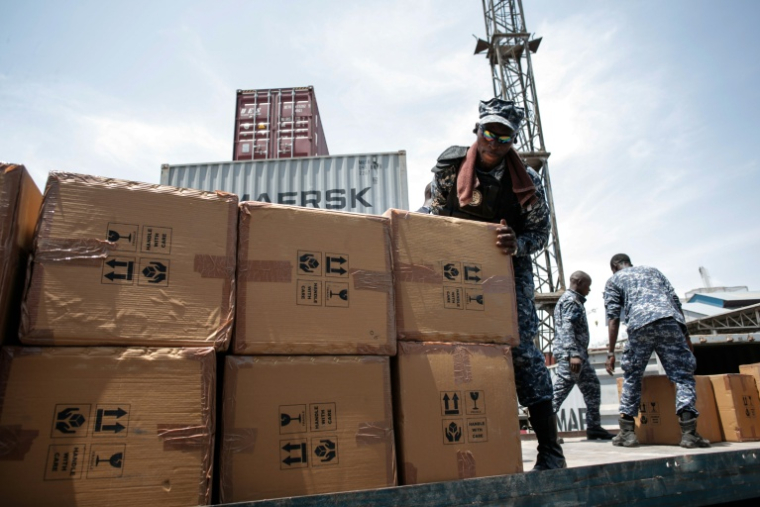 Un membre de l'unité de lutte contre la criminalité organisée transnationale charge des cartons contenant du tapentadol saisis dans des conteneurs en provenance d’Inde, au terminal de Freetown, le 27 mars 2026 en Sierra Leone  ( AFP / Saidu BAH )