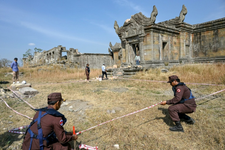 Des démineurs cambodgiens délimitent un périmètre autour d'une munition non explosée, le 6 février 2026, sur le site du temple de Preah Vihear, dans le nord du Cambodge ( AFP / TANG CHHIN Sothy )