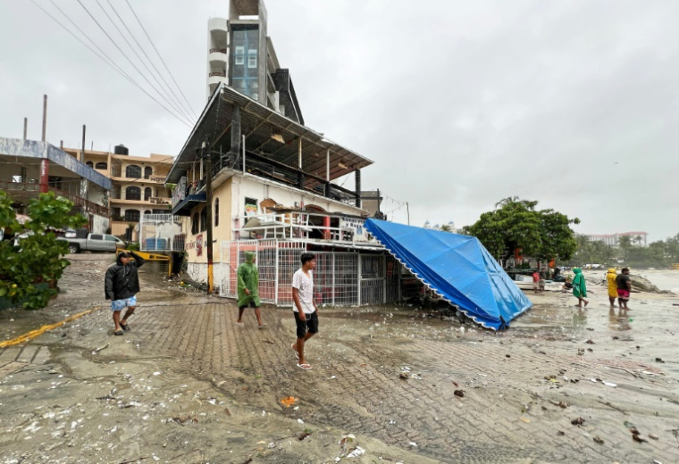 Des habitants constatent les dégâts provoqués par le passage de l'ouragan Erick à Puerto Escondido dans l'Etat du Oaxaca dans l'ouest du Mexique le 19 juin 2025. ( AFP / CARLO ECHEGOYEN )
