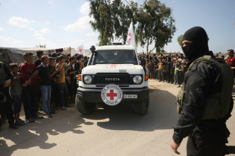 Une foule de Palestiniens observe une voiture du CICR quittant Deir el-Balah, dans le centre de la bande de Gaza, en emmenant des otages israéliens libérés, le 13 octobre 2025 ( AFP / Bashar TALEB )