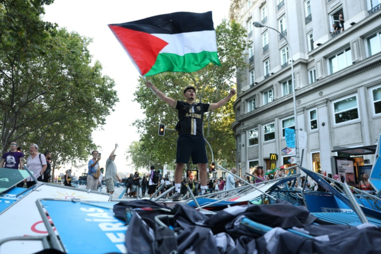 Un manifestant propalestinien brandit un drapeau palestinien alors que les manifestants ont envahi les rues pendant la 21e et dernière étape du Tour d'Espagne cycliste, le 14 septembre 2025 à Madrid ( AFP / Thomas COEX )