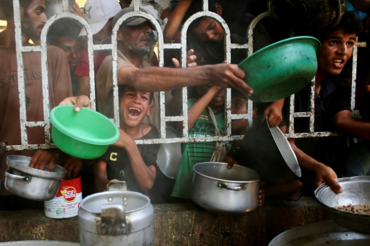 Des Palestiniens dont un enfant en pleurs se bousculent pour recevoir un repas chaud auprès d'une organisation caritative locale à Khan Younès, dans le sud de la bande de Gaza, le 22 juillet 2025. ( AFP / - )